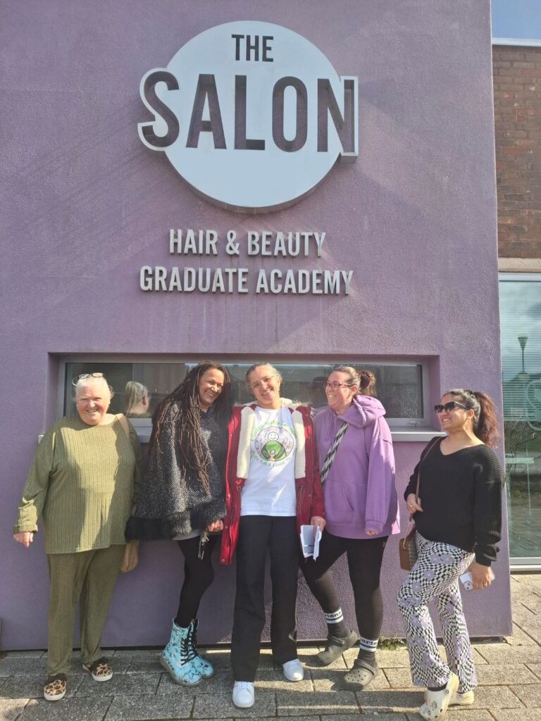 Foster carers standing outside The Salon at Langley College, smiling